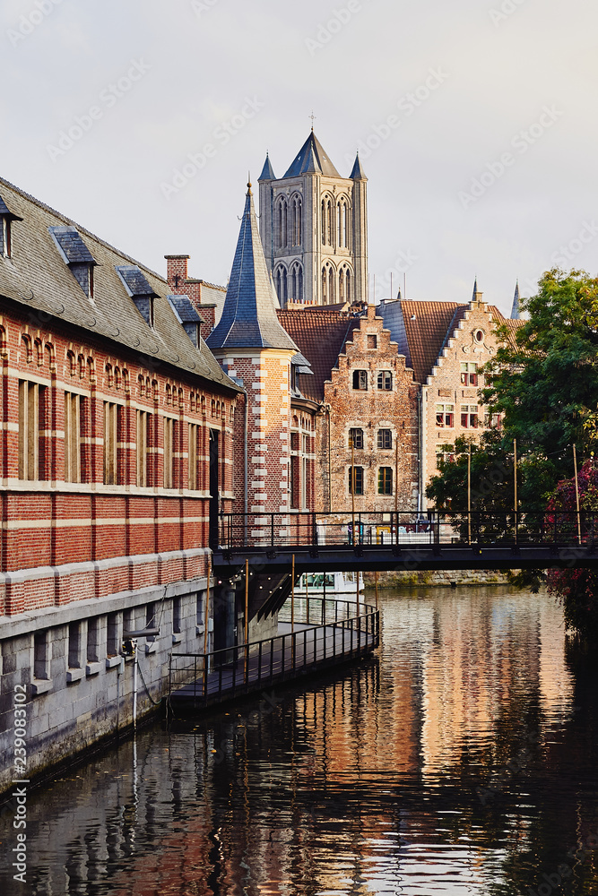 View of water canal, bridge, medieval buildings and tower of St Nicholas' Church in Ghent, Belgium