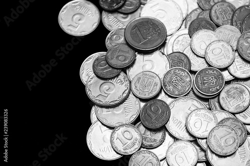 Ukrainian coins with one euro coin isolated on black background. Black and white image. Close-up view. Coins are located at the right side of frame. A conceptual image.