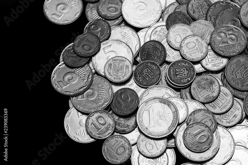 Ukrainian coins with one euro coin isolated on black background. Black and white image. Close-up view. Coins are located at the right side of frame. A conceptual image.