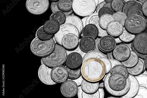 Ukrainian coins with one euro coin isolated on black background. Black and white image. Euro coin is colored. Close-up view. Coins are located at the right side of frame. A conceptual image.