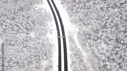 Aerial view of snow covered road in winter forest, truck passing by, motion blur © savantermedia
