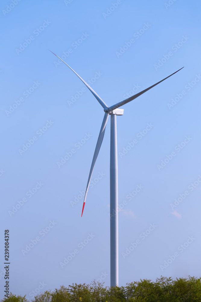 One single windmill turbine with blue sky in background. Renewable energy wind turbine