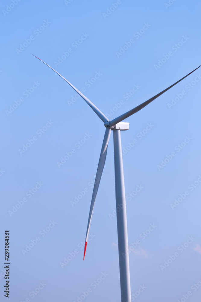 Fototapeta premium One single windmill turbine with blue sky in background. Renewable energy wind turbine