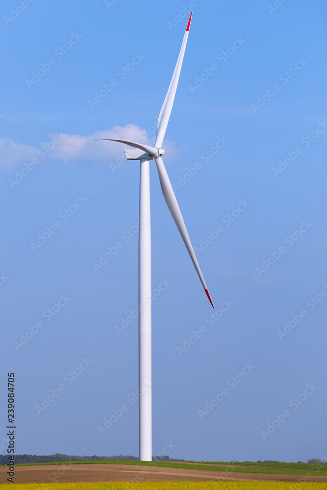 One single windmill turbine on agricultural field with blue sky in background. Renewable energy wind turbine One single windmill turbine on agricultural field with blue sky in background. Renewable energy wind turbine