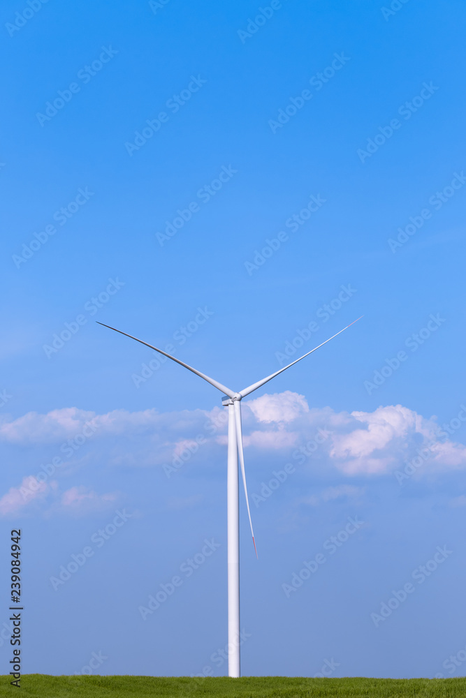One single windmill turbine on green agricultural field with blue sky in background. Renewable energy wind turbine One single windmill turbine on green agricultural field with blue sky in background. Renewable energy wind turbine