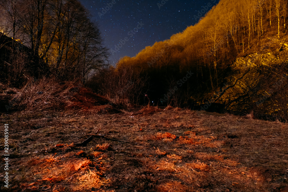 Fototapeta premium Night picturesque view. The wonderful starry sky s time and the majestic mountain range, with glowing villages below. Some digital noise due to high iso.