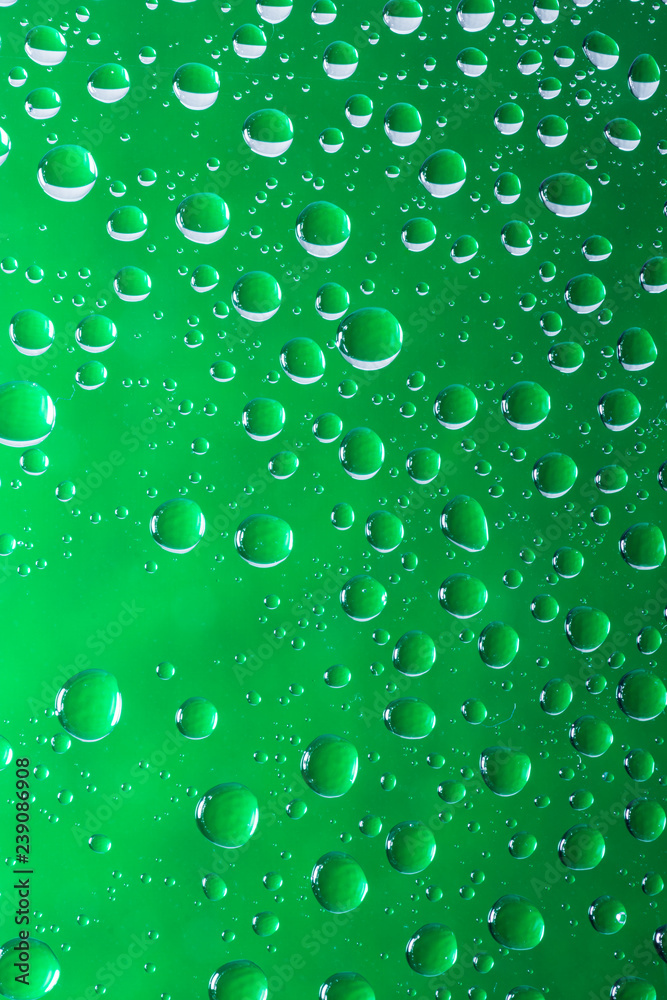 Green water droplets on a glass close up macro shot. Rainy days. 