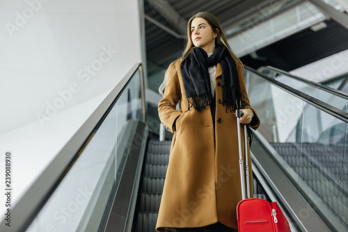 Businesswoman on airport walking up and down on escalator with hand luggage  going to boarding gate. Copy space