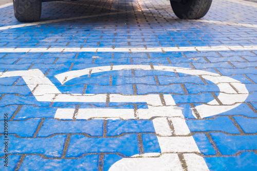 two wheels on the disabled dedicated parking place marked with blue wheel chair symbol