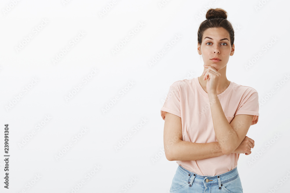 Woman looking with interest at camera as coworker telling good idea might work. Good-looking european female holding hand on chin raising one eyebrow and staring focused thinking listening team plan Woman looking with interest at camera as coworker telling good idea might work. Good-looking european female holding hand on chin raising one eyebrow and staring focused thinking listening team plan
