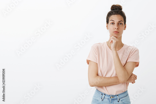 Woman looking with interest at camera as coworker telling good idea might work. Good-looking european female holding hand on chin raising one eyebrow and staring focused thinking listening team plan © Cookie Studio