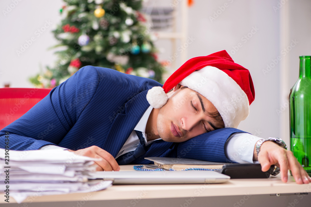 Young handsome employee celebrating Christmas at workplace Young handsome employee celebrating Christmas at workplace