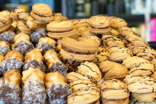 Various biscuits with condensed milk and poured chocolate on sale in a candy store. Dessert for tea or coffee, assorted pastries with chocolate and condensed milk fillings
