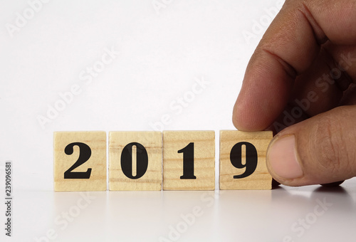 Close up man hand arranging wood block and 2019 written on it.