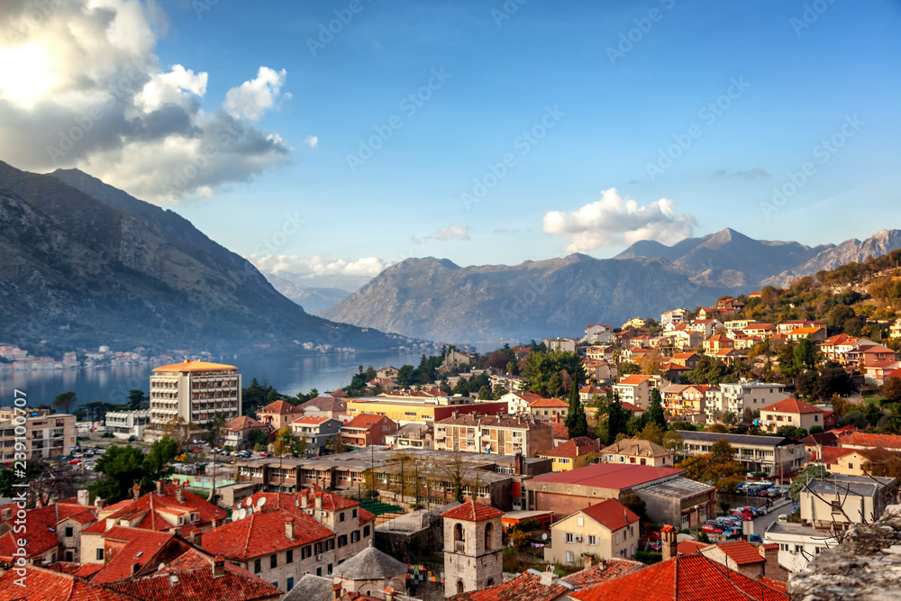 View of the roofs of the houses and the marina with a fortress wall in the old town of Kotor, Montenegro at sunset