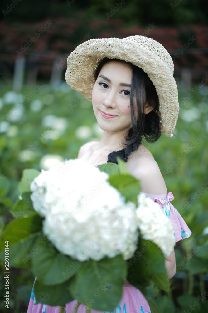 Fototapeta premium Beautiful girl with a field of hydrangea flowers.