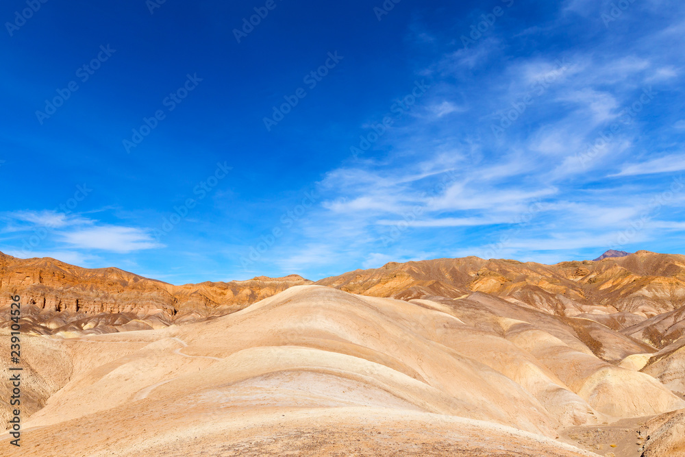 Death Valley National Park panorama near Zabriskie Point. Mountainous landscape of badlands in the morning under blue skies.
