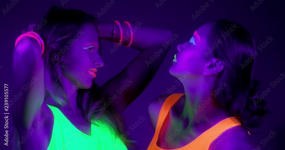 Slow motin of beautiful sexy women with fluorescent make-up and clothing dancing in neon light. Night club, Party Concept. Slow motin of beautiful sexy women with fluorescent make-up and clothing dancing in neon light. Night club, Party Concept.
