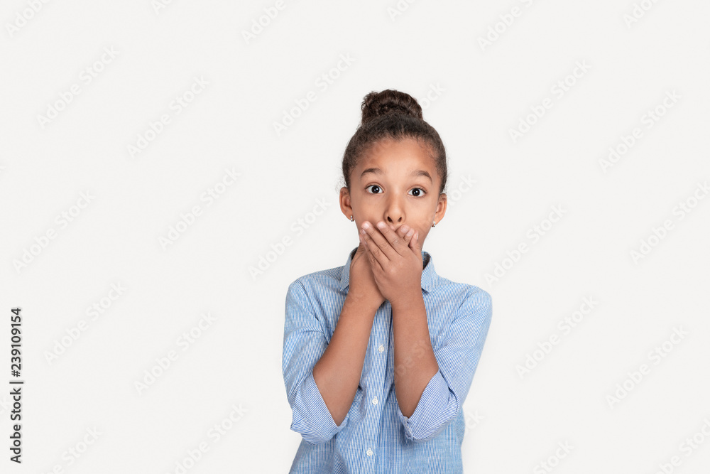 Close up emotional portrait of frizzy girl wearing blue shirt. She holds her cheeks and smiles Close up emotional portrait of frizzy girl wearing blue shirt. She holds her cheeks and smiles