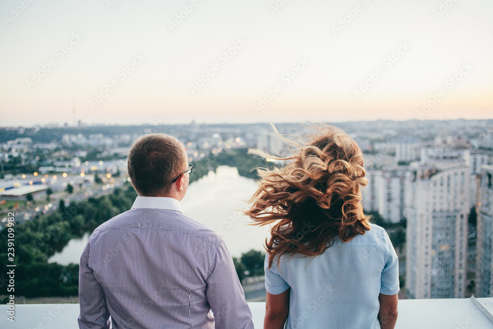 loving couple standing on the roof and watching on the city