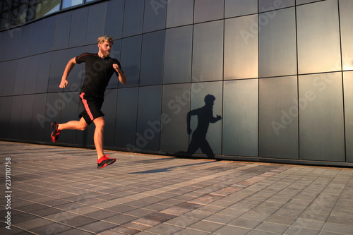 Sporty young man running outdoors to stay healthy, at sunset or sunrise. Runner.