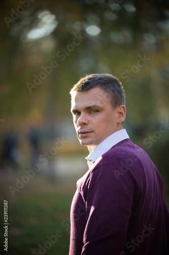 The man looks back at the camera in the autumn park