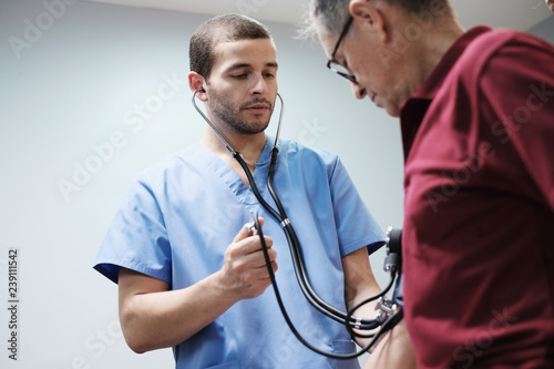Nurse and Doctor Measure Hispanic Old Man Blood Pressure
