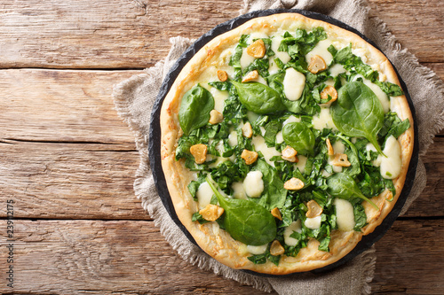 Italian cuisine thin pizza with fresh spinach, garlic and cheese close-up on a board. horizontal top view