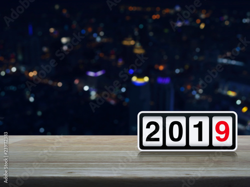 Retro flip clock with 2019 text on wooden table over blur colorful night light modern city tower and skyscraper, Happy new year concept