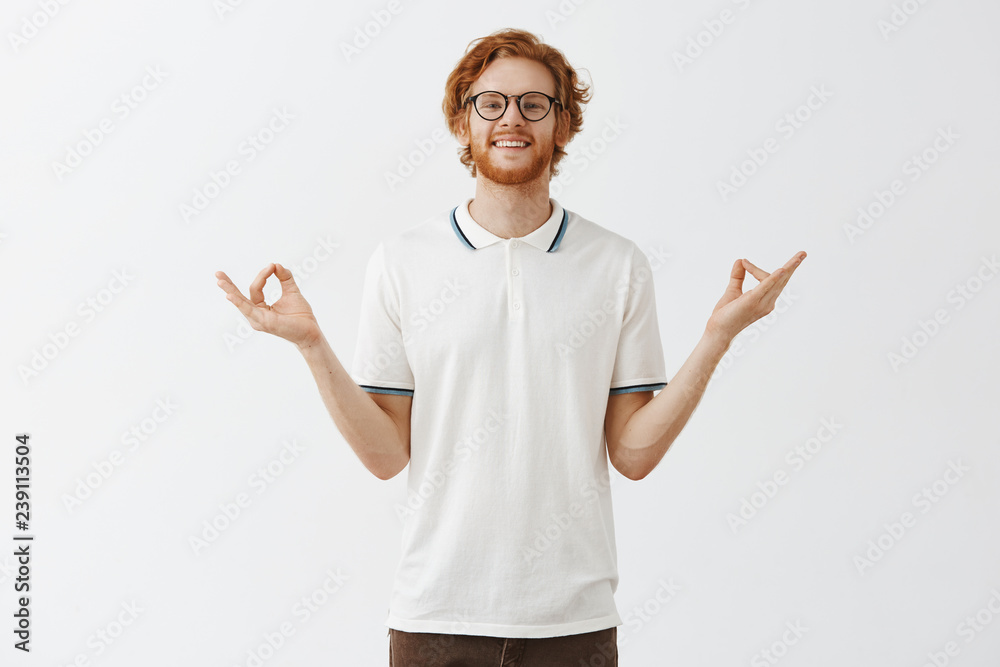 Man is good expample of patience and relaxation. Happy calm good-looking redhead guy with beard in glasses and white casual shirt spreading hands aside in zen gesture meditating and smiling relieved Man is good expample of patience and relaxation. Happy calm good-looking redhead guy with beard in glasses and white casual shirt spreading hands aside in zen gesture meditating and smiling relieved