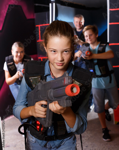 Smiling girl aiming laser gun at other players