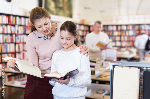 Foto Friendly family of mother and daughter browsing books together in bookstore