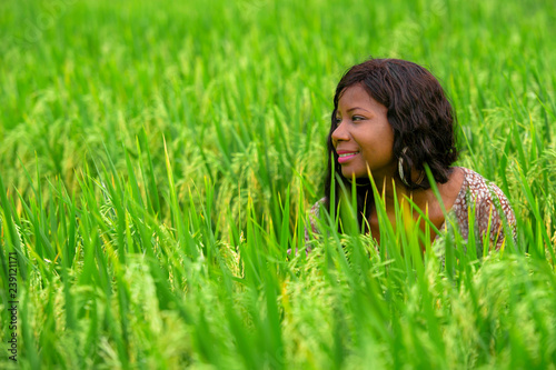 portrait of young beautiful and happy black afro American woman isolated in the middle of rice field enjoying exotic holidays trip in Asia exploring traditional village