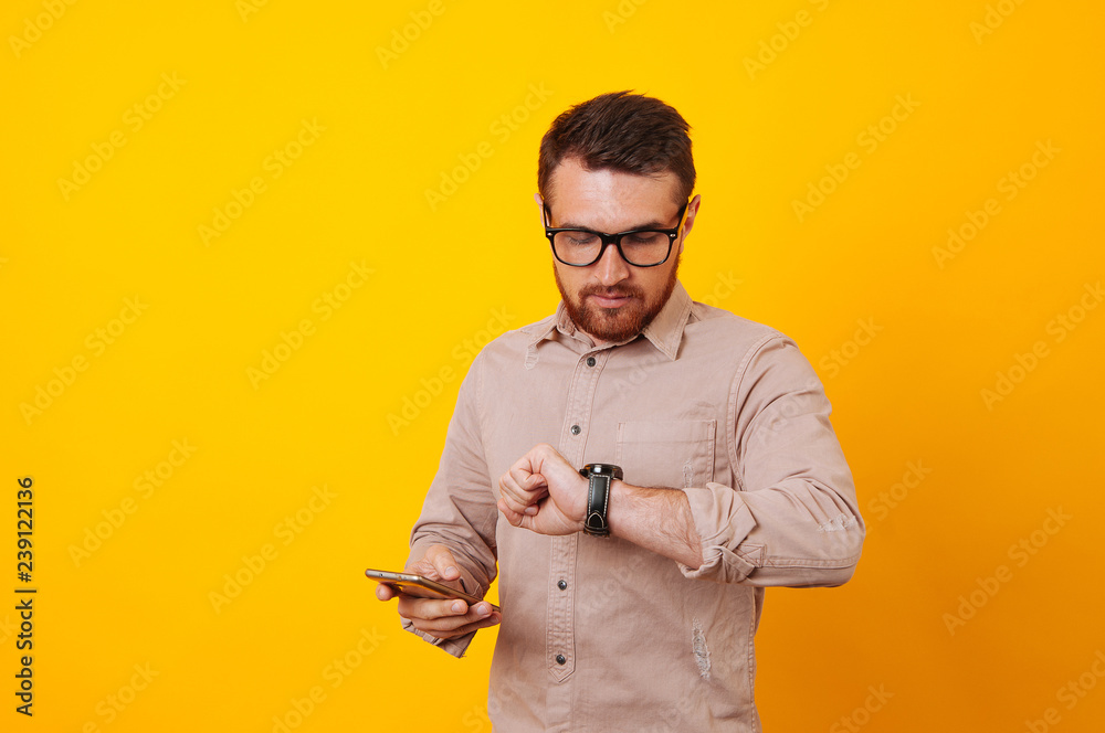 Photo of man looking at watch and hold mobile in hand Photo of man looking at watch and hold mobile in hand