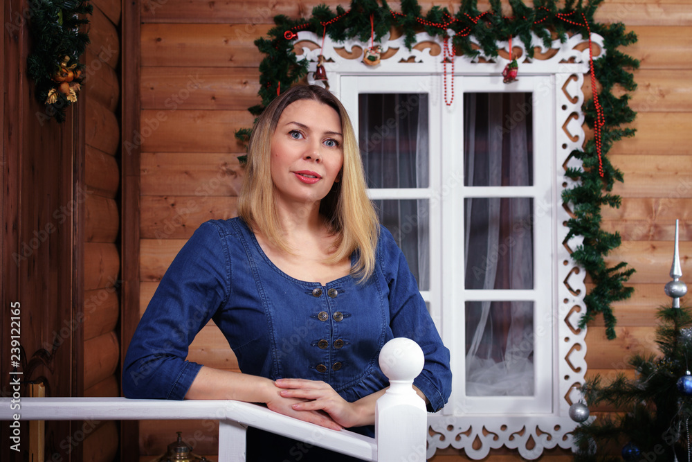 Beautiful young woman is standing on the porch of a house decorated for ...