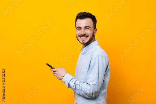 Happy young man is smiling and hold in hands a mobile