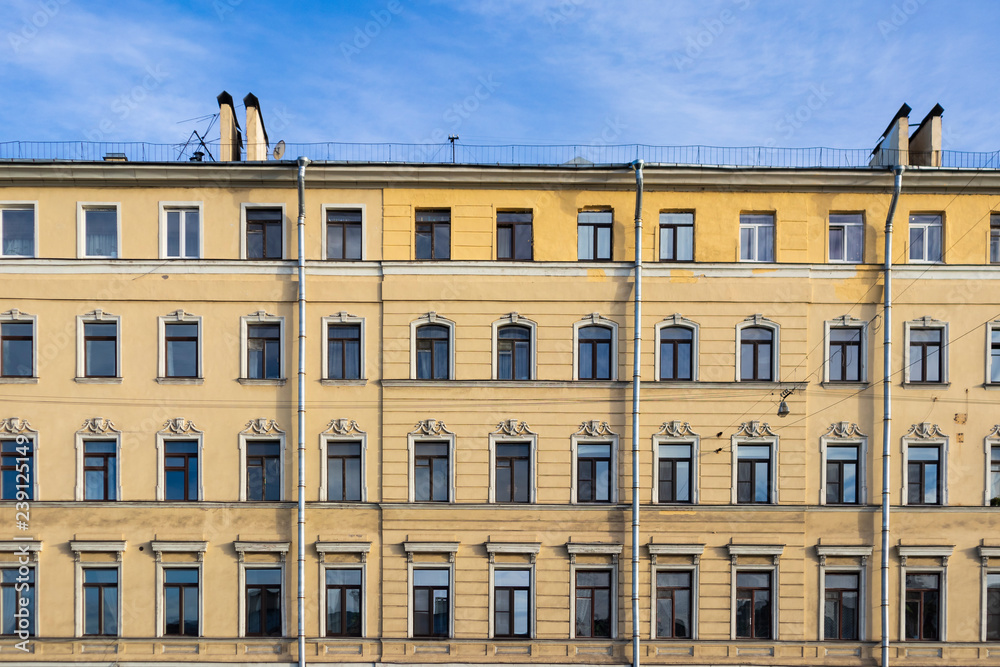 Fototapeta premium Old building facade with windows on a blue sky