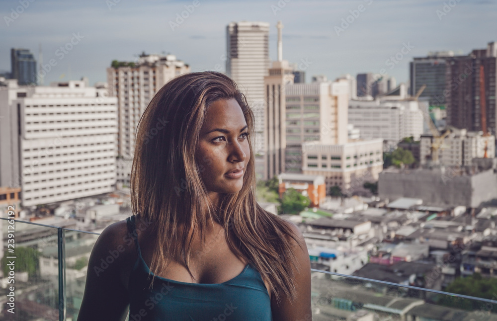 Young female model in front of the city skyline of Bangkok in Thailand.