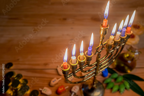 Jewish holiday hanukkah celebration with menorah (traditional candelabra), wooden dreidels (spinning top), donut, olive oil and chocolate coins on wooden table.