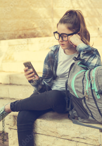 Portrait of tenage girl sitting outdoor with mobile phone photo