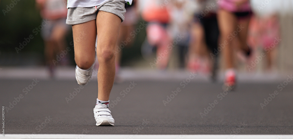 Running children, young athletes run in a kids run race,running on city road detail on legs, goal of the run