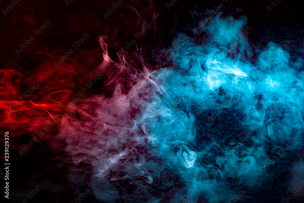 Dynamic clouds of multi-colored smoke of blue gray and orange on a black background smoothly flow with colorful waves, drawing isolated an column of smoke. Decorative wallpaper with rainbow steam.