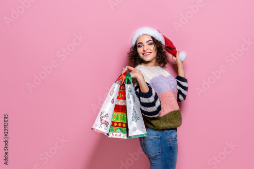 Beautiful women wearing bright Christmas carrying colorful shopping bags. On pink background. Christmas shopping And happy new year. There are many discounts many stores around the world.