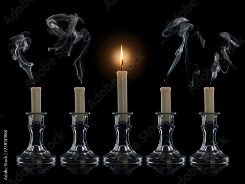 Four extinguished candles and one burning candle