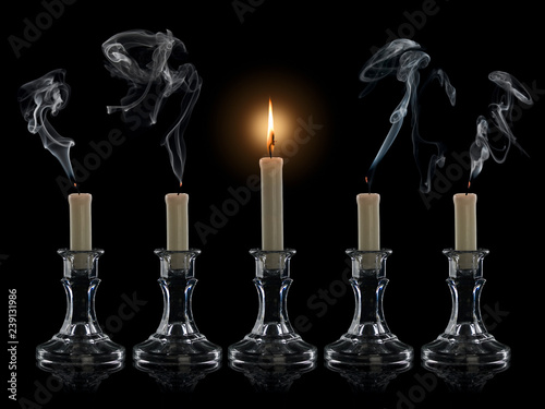 Four extinguished candles and one burning candle photo