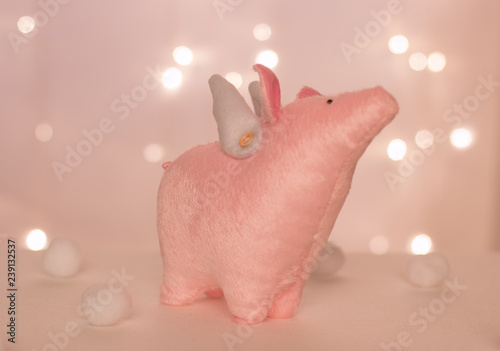 beautiful and tender piggy angel with handmade wings stands against the background of new year lights and soft balls photo