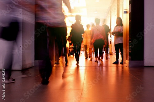 Abstract of people group are walking into the building with flare light and reflection on passageway, back side view and blur motion 