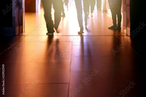 Silhouette human legs are walking into the building with flare light and shadow on surface of passageway in city lifestyles concept, blur motion
