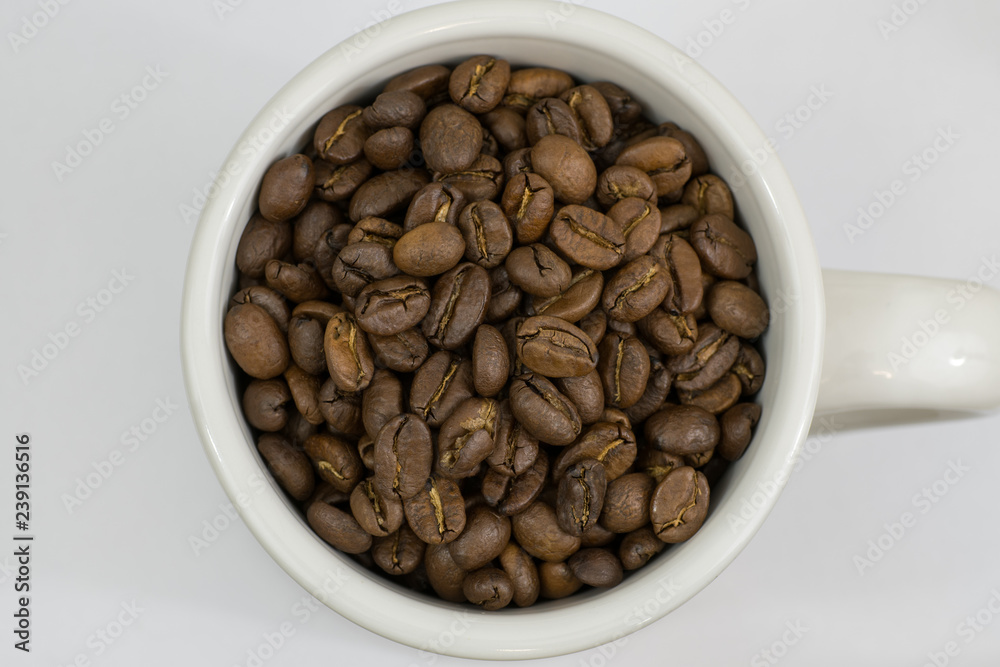 Roasted coffee beans in a white mug cup Roasted coffee beans in a white mug cup