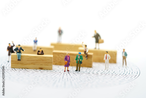 Miniature people: Business team standing on center point of maze and thinking how to solve this problem. Concepts of finding a solution, problem solving and challenge.